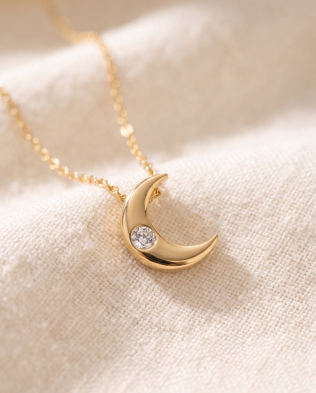 Close-up of the polished crescent moon pendant and its small cubic zirconia stone