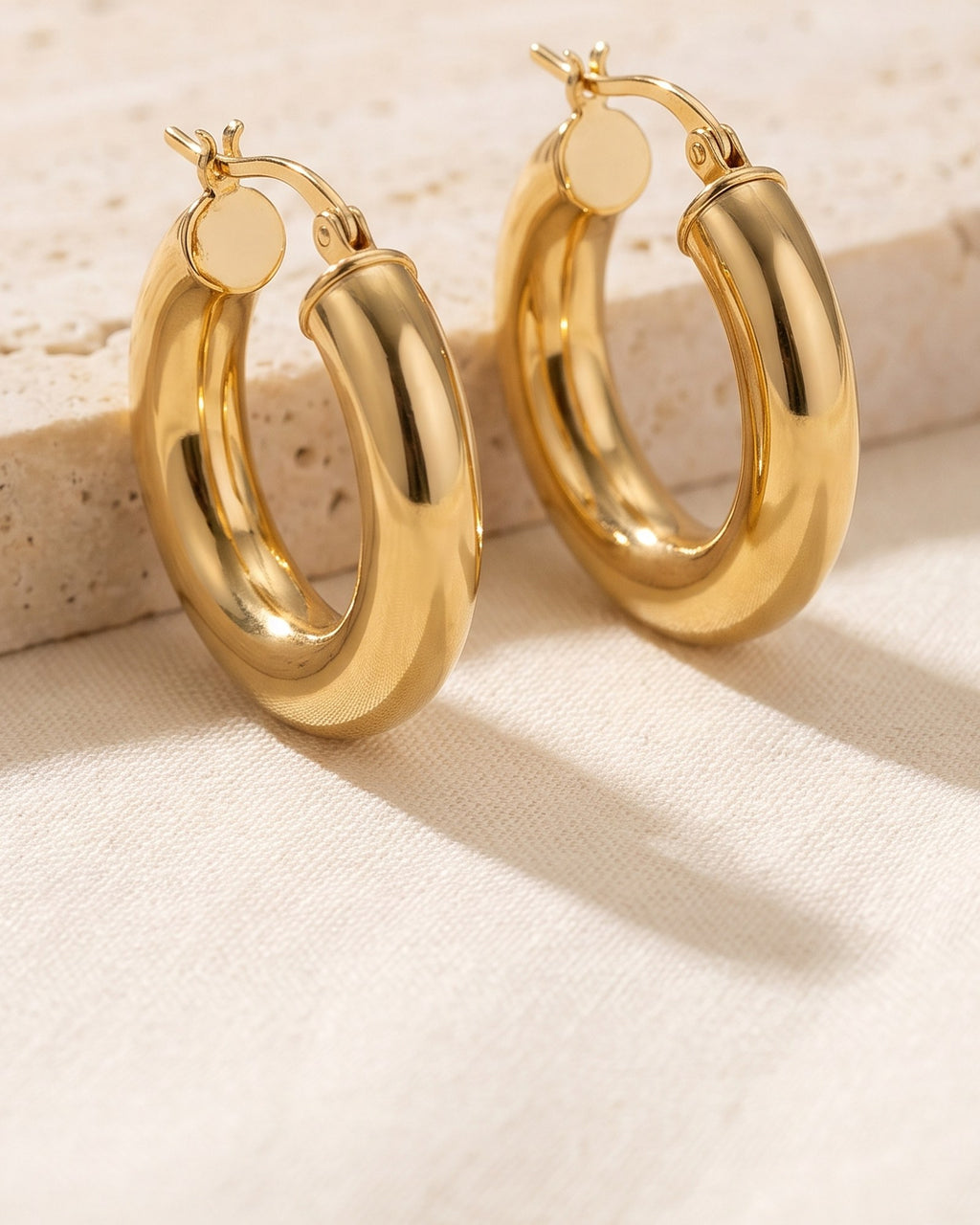 Close-up of the rounded polished surface and hinged closure of the Dome Hoop Earrings