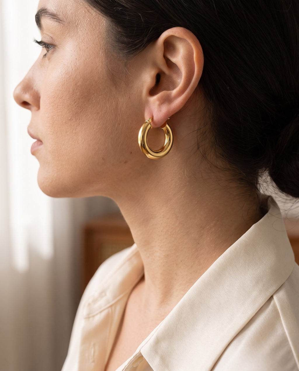 Woman wearing the gold-plated Dome Hoop Earrings with her hair tucked behind the ear