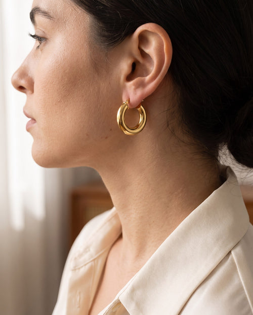 Woman wearing the gold-plated Dome Hoop Earrings with her hair tucked behind the ear