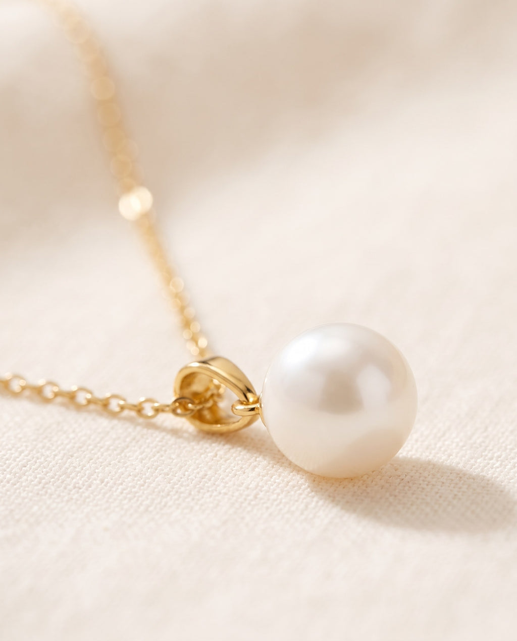 Close-up of the white glass pearl and gold-plated bail of the Glass Pearl Drop Necklace