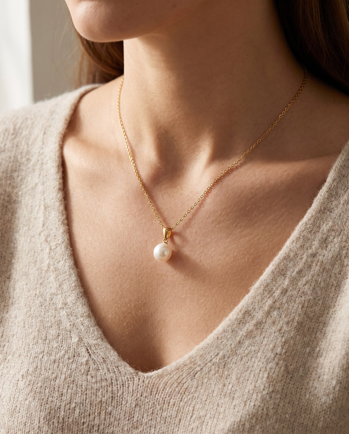 Woman wearing the Glass Pearl Drop Necklace with a soft knit jumper