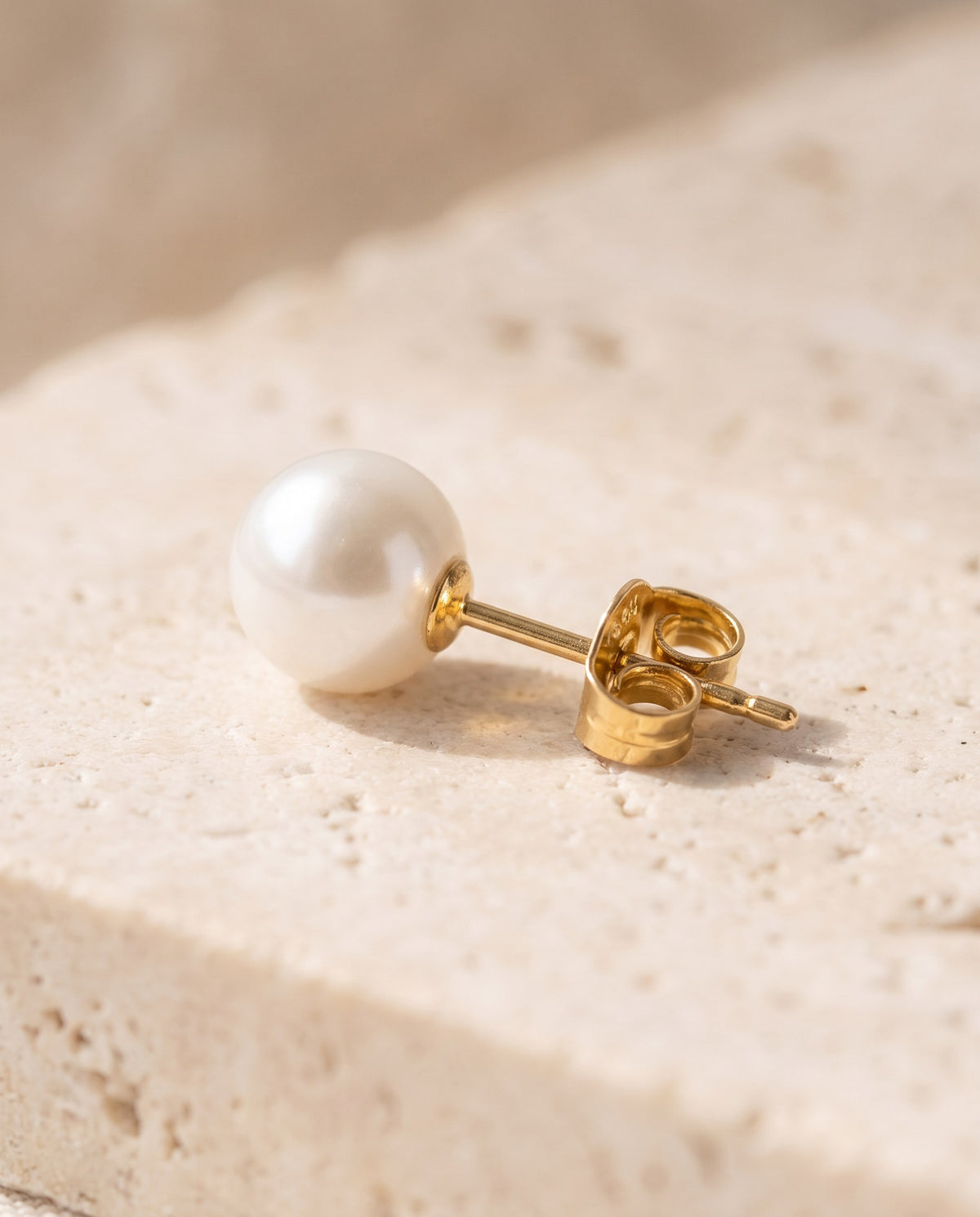 Close-up of the lustrous white glass pearl and gold-plated post of the stud earrings