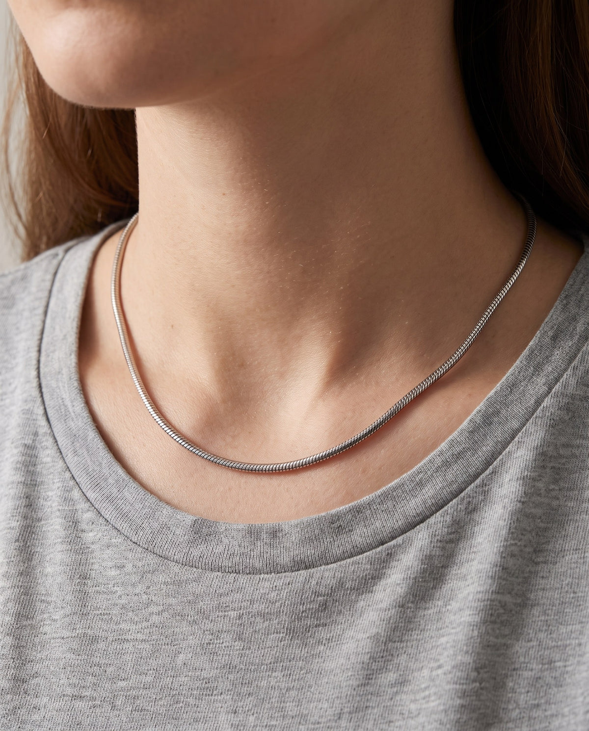 Woman wearing the silver-tone Snake Chain Necklace with a grey round-neck top